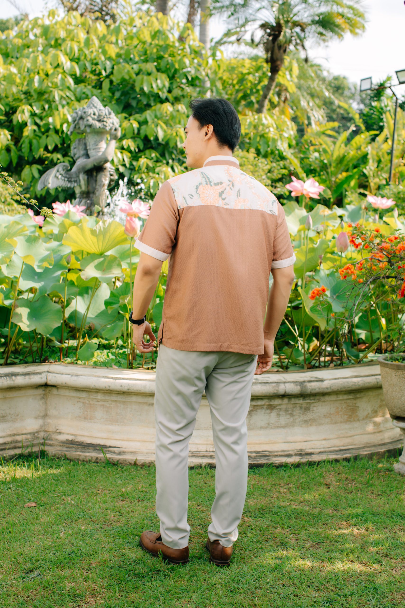 Model mengenakan koleksi Blooming Raya Series dari Batik Iskandartex dengan motif floral elegan di taman