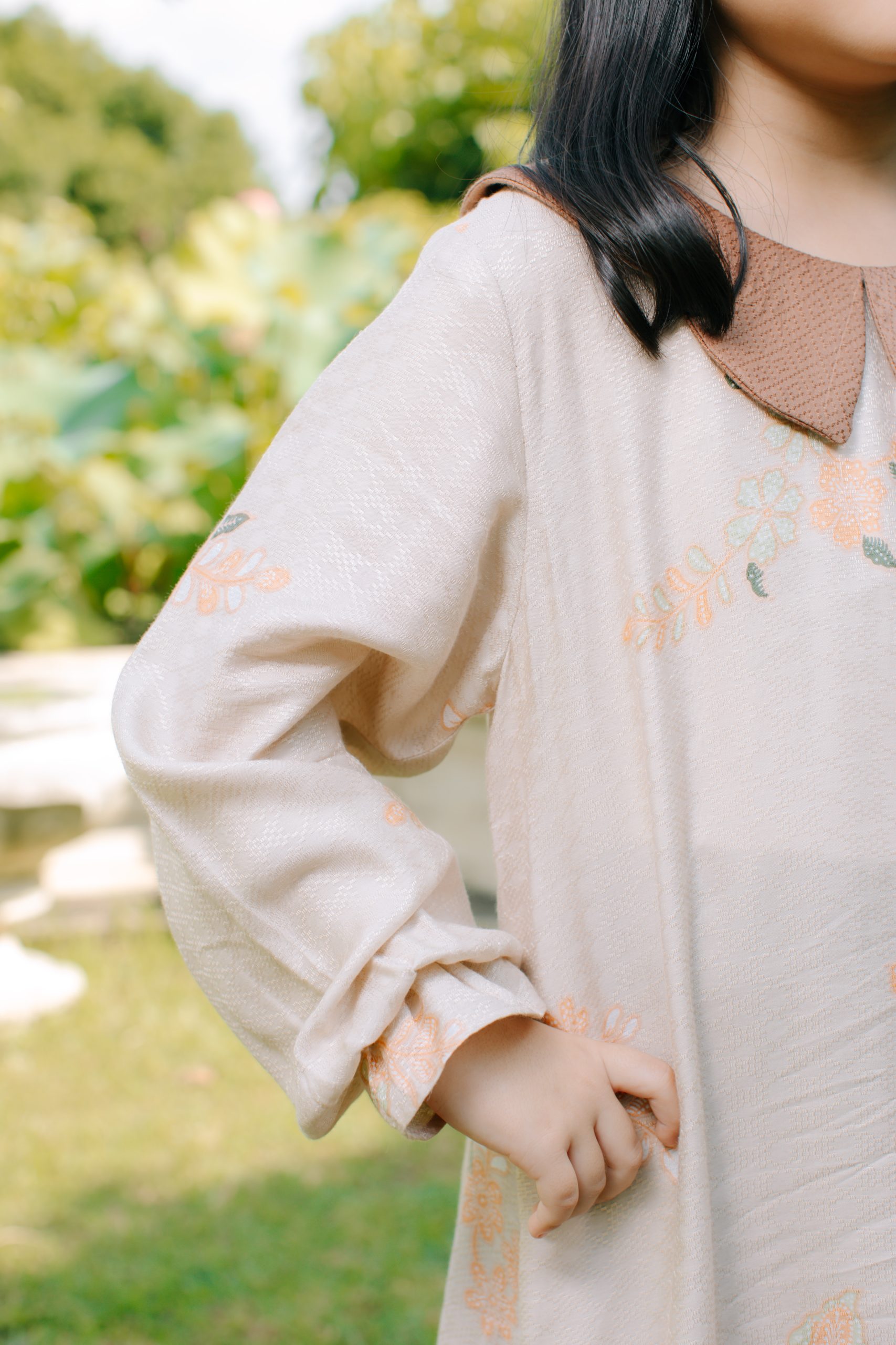 Model mengenakan koleksi Blooming Raya Series dari Batik Iskandartex dengan motif floral elegan di taman