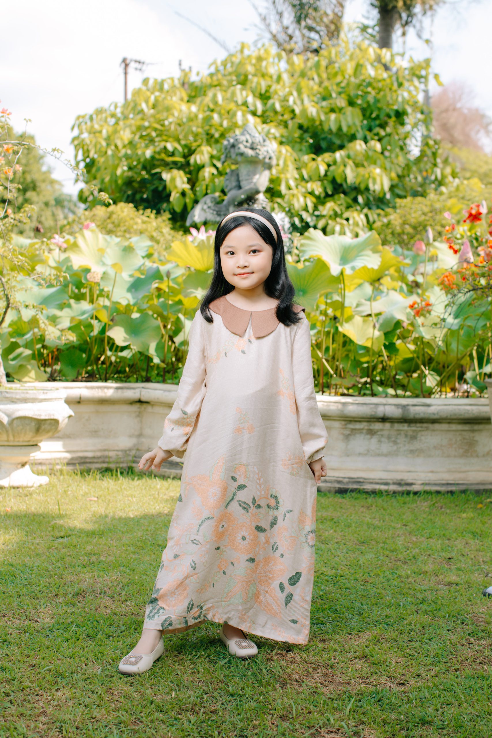 Model mengenakan koleksi Blooming Raya Series dari Batik Iskandartex dengan motif floral elegan di taman